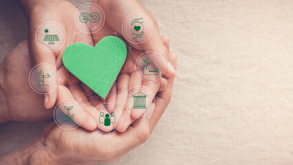 Hands holding green heart with eco circular economy icons, CSR social responsibility, ESG, eco...