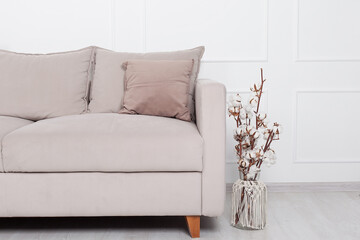 A large sofa in beige tones with a beautiful large potted bush.