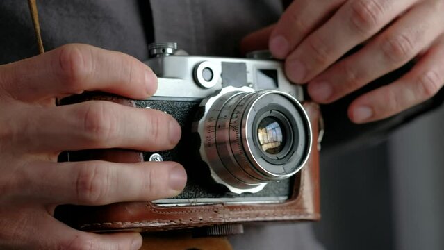 Person photographer holding in hands vintage photo camera. Close-up. Setting options.