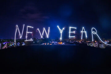 Happy new year light motion letters on the cityscape background.  Modern Holiday card