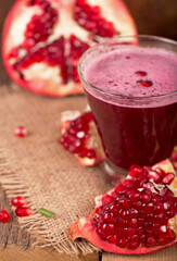 Juicy pomegranate and a glass of pomegranate juice Beautiful composition with juicy pomegranates, on old wooden table
