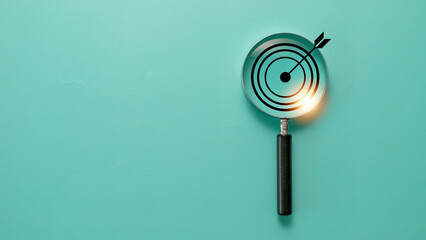 Target board inside of magnifier glass for focus business objective on blue background and copy space.