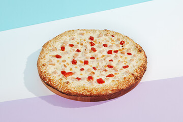 Italian pizza with chicken and paprika on coloured background. Cheese pizza with chicken and corn in minimal style on blue and purple color. American pizza delivery concept with color backdrop