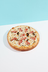 Italian pizza with mushroom and bacon on coloured background. Mushroom pizza with bacon in minimal style on blue and orange color. American pizza delivery concept with color backdrop
