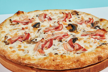 Italian pizza with mushroom and bacon on coloured background. Mushroom pizza with bacon in minimal style on blue and orange color. American pizza delivery concept with color backdrop