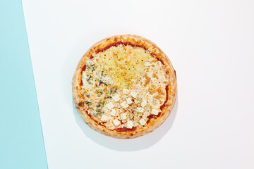 Italian pizza with four cheese on coloured background. Quattro formaggi pizza in minimal style on...