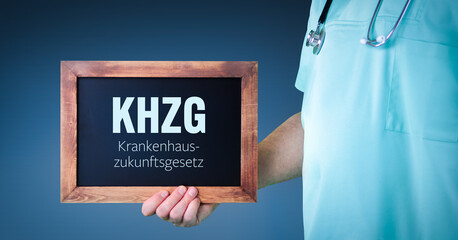 KHZG (Krankenhauszukunftsgesetz). Arzt zeigt Schild/Tafel mit Holz Rahmen. Hintergrund blau