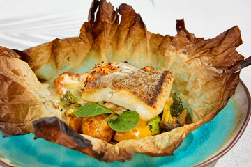 Baked halibut fillet with vegetables in parchment. Fish dish - roasted halibut with potato,...