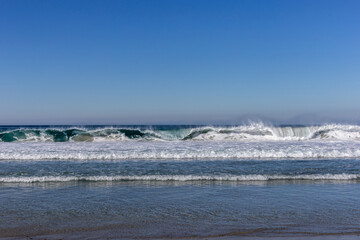 A view on ocean with white waves and blue sky