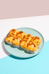 Hot sushi roll with cream cheese top and crispy onion. Baked sushi with salmon, cream cheese topped. Hot maki sushi  on coloured background in minimal style.