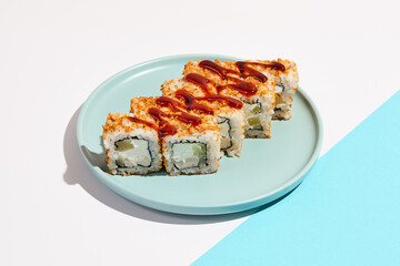Sushi roll with chicken, cucumber and cheese inside, crispy onion outside. Maki sushi with chicken on ceramic dish. Alternative maki sushi  on coloured background in minimal style. Sushi no fish.