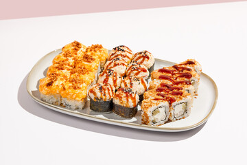 Set of hot maki sushi on ceramic dishware. Baked sushi set in minimal style. Tempura rolls in modern concept. Japanese menu in modern style.