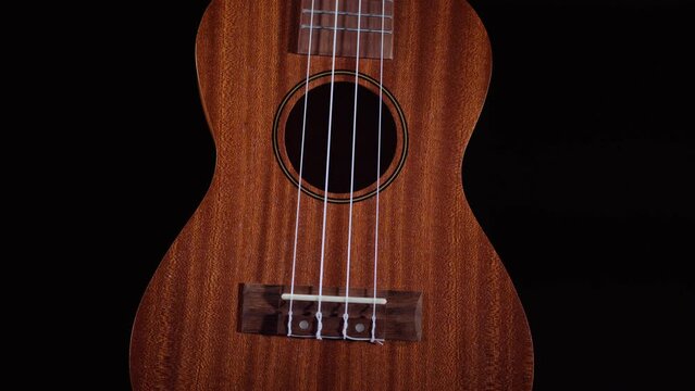 Ukulele on black background. 
Ukulele string instrument