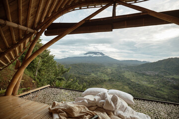 Bed on a hammock with a beautiful view of the mountains from a bamboo house. Bamboo house with mountain or volcano view in Bali.