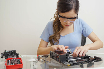 Asian Woman installing or repairing CPU in a socket on the computer motherboard gaming.