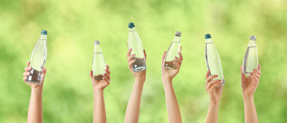 Female hands with bottles of water on blurred green background