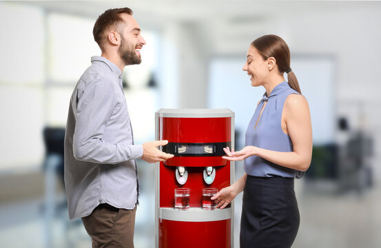 Man and woman talking near water cooler in office