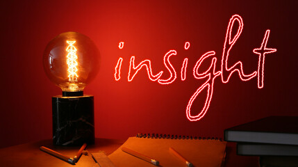 Glowing lamp, stationery and word INSIGHT on red background