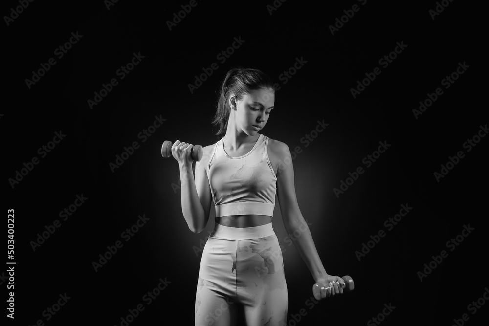 Poster black and white portrait of beautiful sporty young woman with dumbbells on dark background