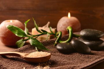 Spoon with sea salt, spa stones and clean towel on table