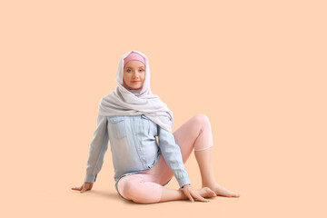 Pregnant Muslim woman practicing yoga on beige background