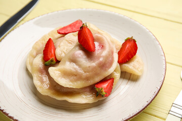 Plate with delicious strawberry dumplings on color wooden background, closeup