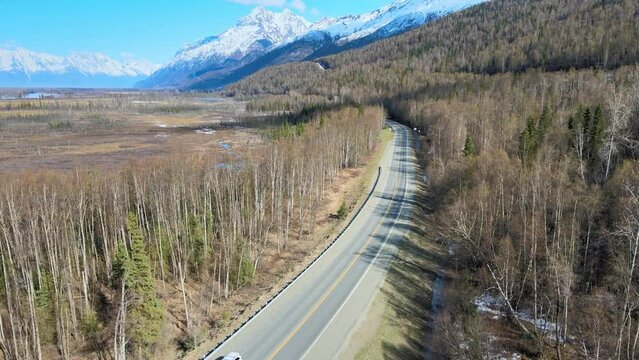 Aerial view of country road with mountains on the right and swamp on the left in the spring prior to the foliage turning green.