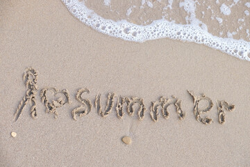 Text I LOVE SUMMER written on wet sand beach, top view