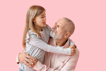 Little girl with her grandfather hugging on pink background