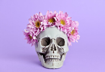 Human skull with flowers on purple background