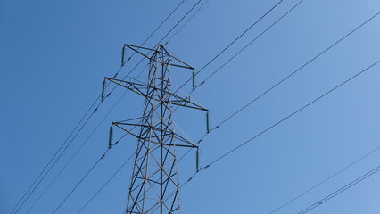 View of electricity pylon against deep blue sky with copy space
