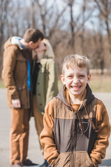 smiling little boy in front. kissing parents on background