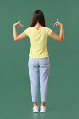 Pretty young woman in stylish t-shirt on green background, back view