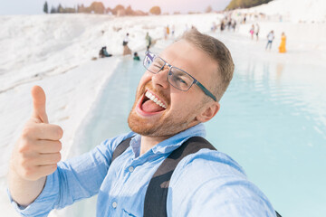 Happy tourist man with backpack on background denizli travertine pools blue water in Pamukkale Turkey