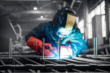 Welder in protective uniform with mask. Factory industrial worker on workplace with spark