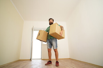 Fototapeta na wymiar Man carrying cardboard box on moving day. Delivery man loading cardboard boxes for moving to an apartment.