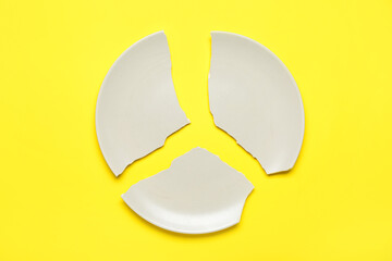 Broken ceramic plate on yellow background