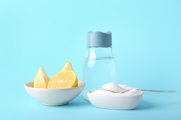 Bowls with baking soda, ripe lemon and bottle of water on color background