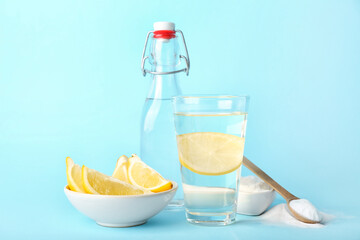 Glass of water, bowl with lemon and baking soda on color background