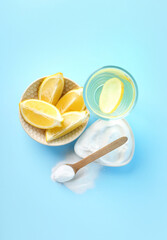 Bowl with lemon slices, baking soda and glass of water on color background