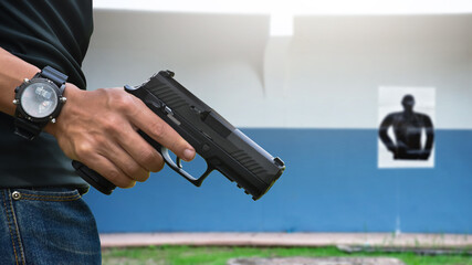 9mm automatic pistol holding in right hand of shooter at the shooting range, concept for security, robbery, gangster, bodyguard training. selective focus on pistol.