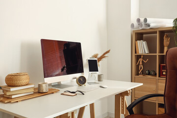 Workplace with modern gadgets near light wall