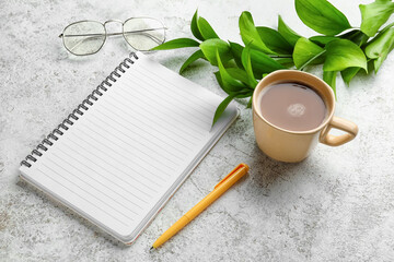 Notebook, cup of coffee, glasses and pen on light background