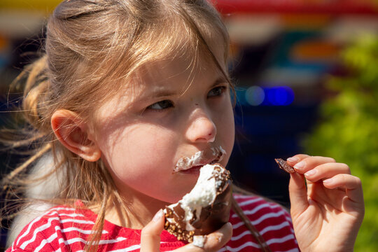 Siebenjähriges Mädchen isst einen Schokokuss auf einem Volksfest (model released)