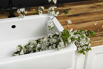 Beautiful blooming tree branches in sink on wooden table