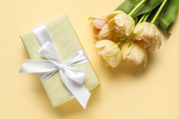 Beautiful flowers with gift box on beige background