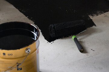 Applying hot resin to the floor for waterproofing, roller and bucket of resin.