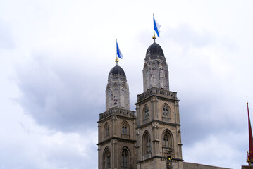 Obraz premium Old town of City of Zürich with protestant church Great Minster with flags on a rainy spring day. Photo taken April 24th, 2022, Zurich, Switzerland.