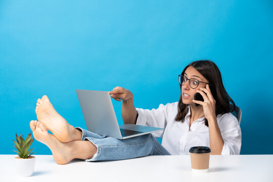 Young hispanic woman working feet on desk isolated on blue background. Boss giving orders on phone.