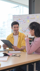 Two young employees brainstorming and discussing ideas of the new startup project together at modern office.